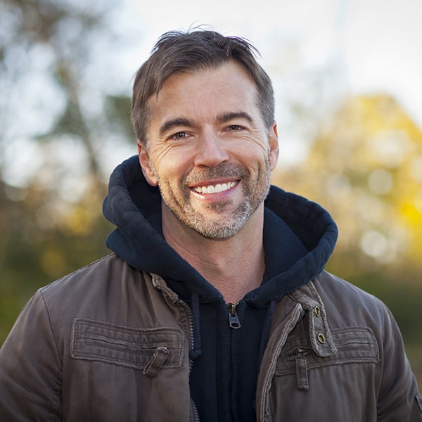 A mature man smiling in a park