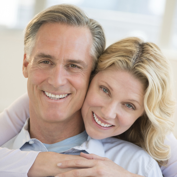 A middle-aged couple embrace and smile after their comprehensive exam with Hazen Smiles